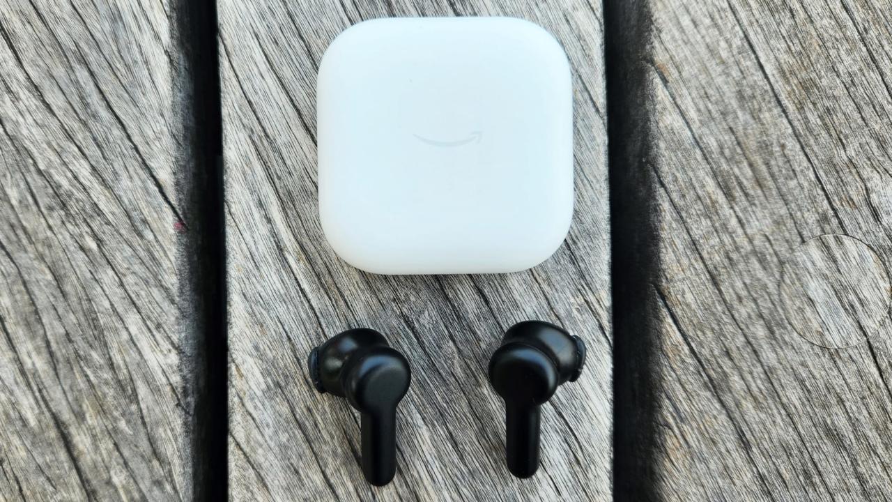 The Amazon echo buds are arranged on a gray wood deck. 