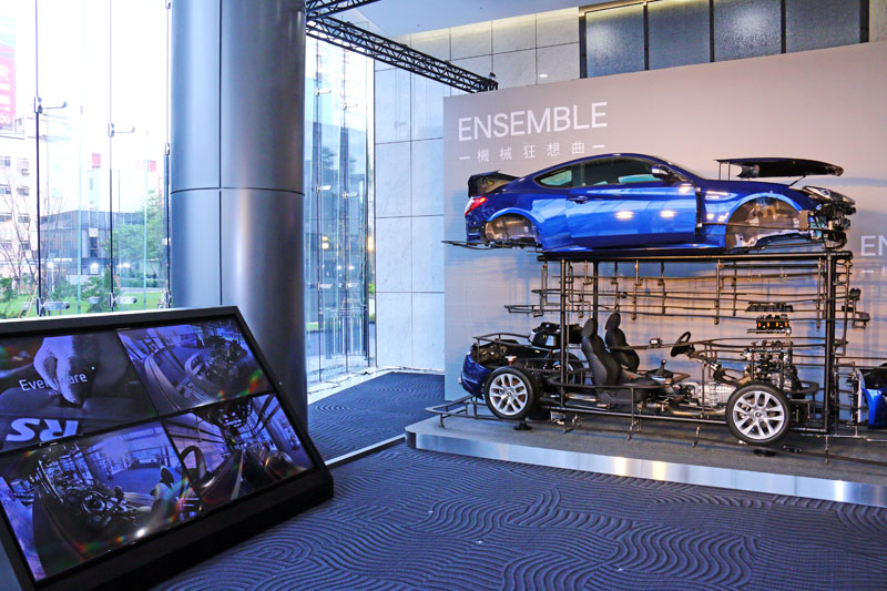 “Ensemble 機械狂想曲”除了右側拆解的車輛外，左側的大螢幕也是也是此件藝術品的一部分。