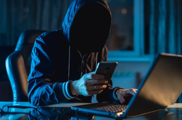 Anonymous hacker programmer uses a laptop to hack the system in the dark. Creation and infection of malicious virus. The concept of cybercrime and hacking database