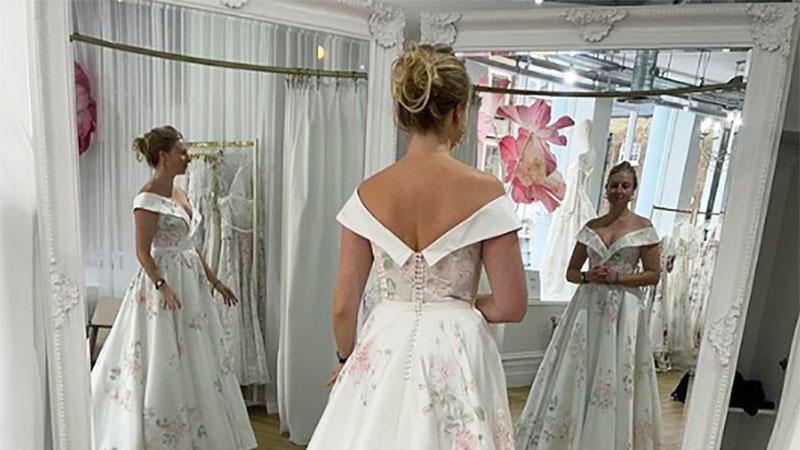 A woman in front of a dual mirror represented as three women, each with different arm positions.   