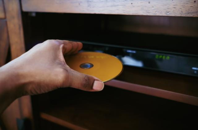 Close-up of unrecognizable black woman inserting disk into DVD player