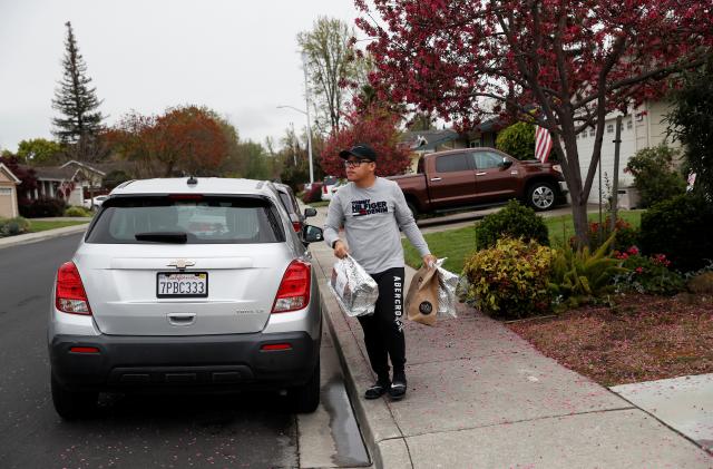 Excelso Sabulau, a 35-year-old independent contract delivery driver for Amazon Flex, carries deliveries to a house, as spread of the coronavirus disease (COVID-19) continues, in Dublin, California, U.S., April 6, 2020. Picture taken April 6, 2020. REUTERS/Shannon Stapleton