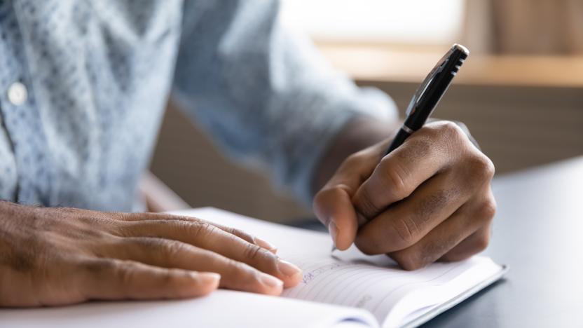 Close up view of african left-handed businessman writing in notebook, american male hands holding pen making notes planning new appointments information in organizer personal paper planner at desk