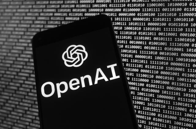 The OpenAI logo appears on a mobile phone in front of a computer screen with random binary data, Thursday, March 9, 2023, in Boston. (AP Photo/Michael Dwyer)