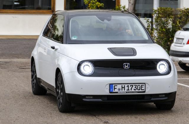 A white compact vehicle with a black roof in the parking lot.