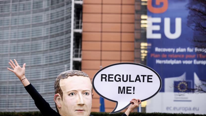 An activist of environmental NGO Avaaz wearing a mask depicting Facebook CEO Mark Zuckerberg holds a banner reading "Regulate me" during an action marking the release of the Digital Services Act, outside the European Commission building in Brussels on December 15, 2020. - The European Union on December 15, 2020 will unveil tough draft rules targeting tech giants like Google, Amazon and Facebook, whose power Brussels sees as a threat to competition and even democracy. (Photo by Kenzo TRIBOUILLARD / AFP) (Photo by KENZO TRIBOUILLARD/AFP via Getty Images)