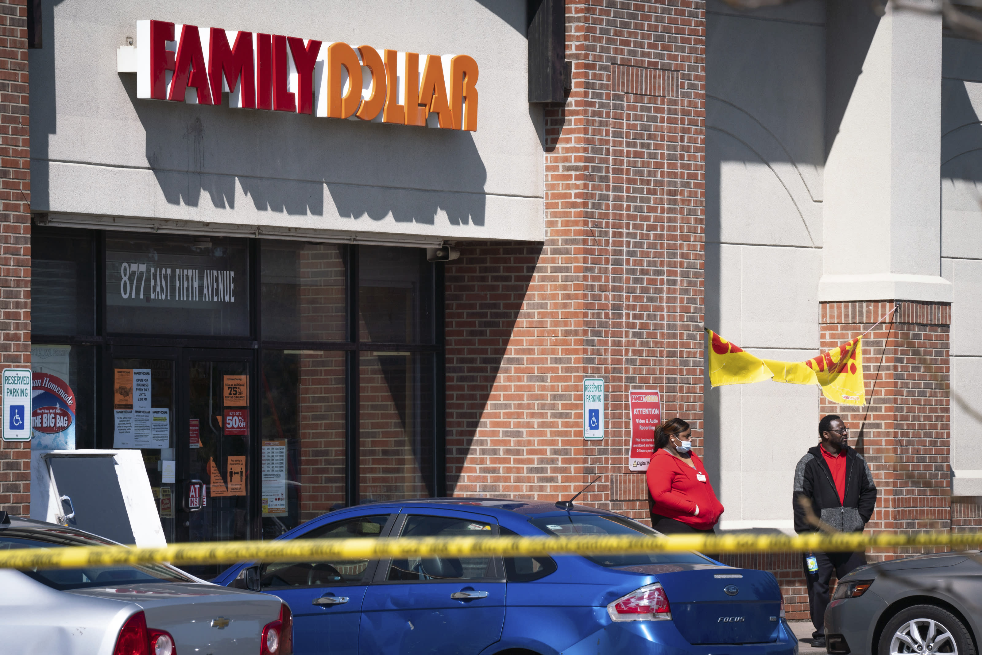 In this Friday, May 1, 2020 photo, employees stand outside the Family Dollar as police investigate a shooting that took place at the store in Flint, Mich. (Sarahbeth Maney/The Flint Journal via AP)