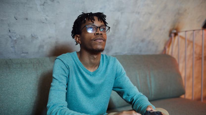 Portrait of smiling African-American man playing videogames via gaming console, copy space