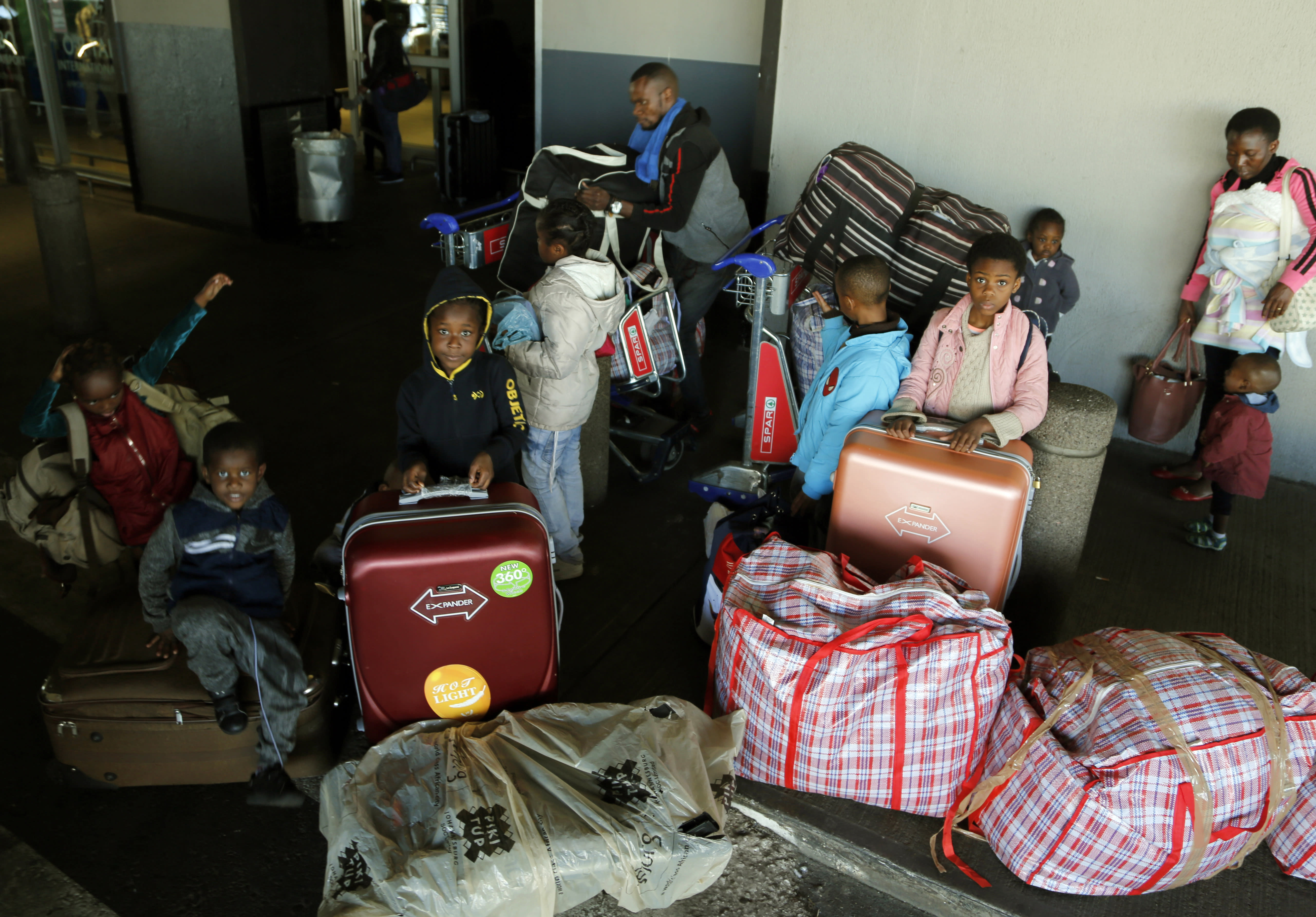 Nigerian children sit on their luggage at the O.R. Tambo International Airport in Johannesburg, South Africa, Wednesday, Sept. 11, A group of Nigerians boarded a free flight from Johannesburg to Lagos on Wednesday, following a week of violence targeting foreigners in South Africa that has stoked tensions between Africa’s two largest economies. It was not immediately clear how many people were on board the flight, operated by the private Nigerian airline Air Peace, but Nigeria’s government said it estimated 313 people would board.2019. (AP Photo/Denis Farrell)