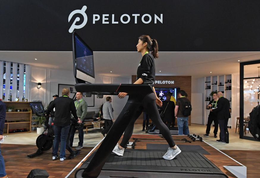 A woman walks on a Peloton treadmill in the Peloton showroom.