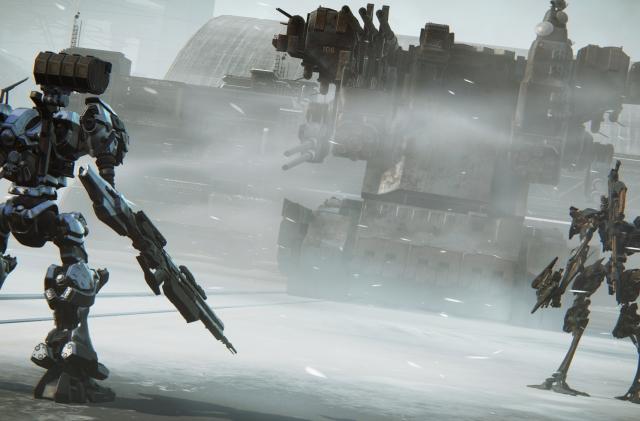 Gameplay screenshot from ‘Armored Core VI: Fires of Rubicon.’ A mech (facing away from the camera) stands to the left of the screen, with a smaller one to the right. A huge tank looms in the background, dominated by bleak, industrial grays.