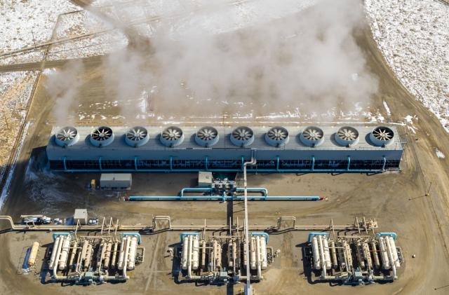 A geothermal power system showing steam rising from vents with snow surrounding it.