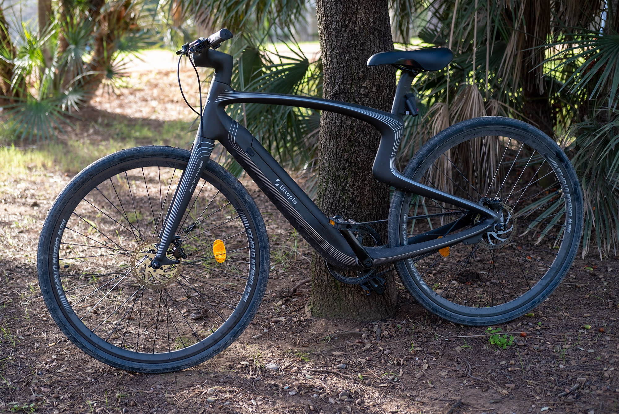 Urtopia's distinctive ebike is pictured resting against a tree.