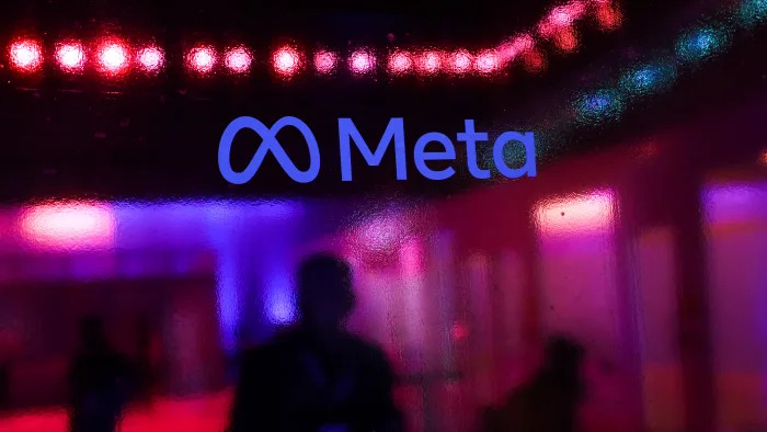 People walk behind a logo of Meta Platforms company, during an event in Mumbai, India, 20 September, 2023 (Photo by Niharika Kulkarni/NurPhoto via Getty Images)