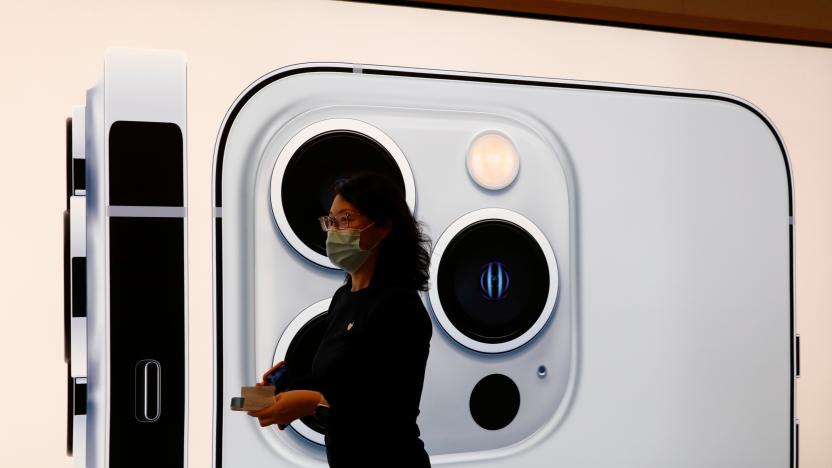 An Apple employee wearing a face mask walks past an image of an iPhone 13 Pro at an Apple Store on the day the new Apple iPhone 13 series goes on sale, in Beijing, China, September 24, 2021. REUTERS/Carlos Garcia Rawlins