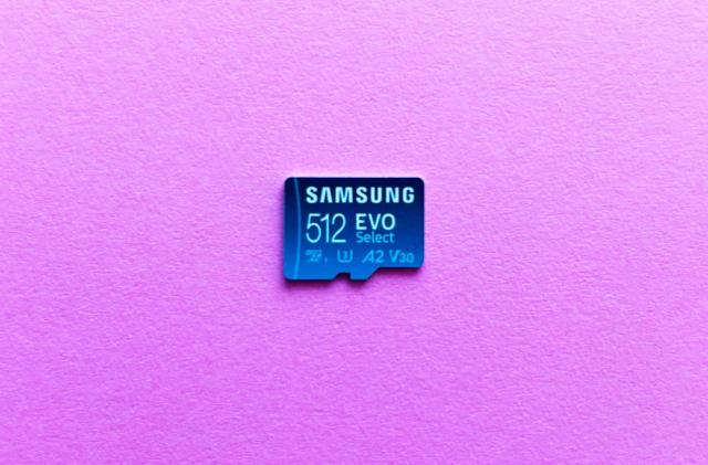 A light blue microSD card, the Samsung Evo Select, rest against a pink background.  