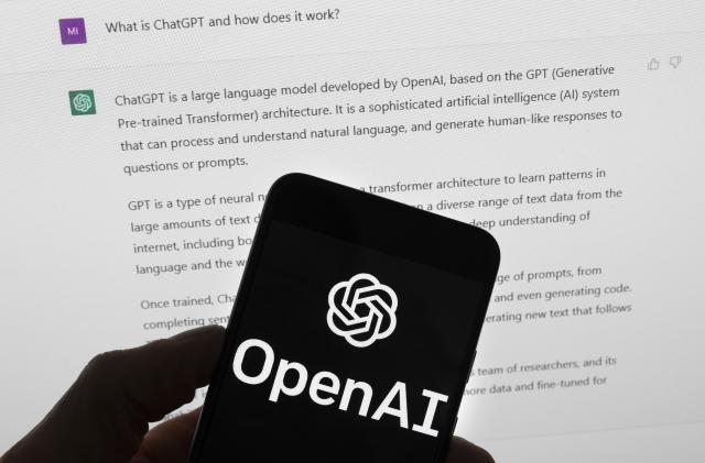 El logotipo de OpenAI puede apreciarse en un teléfono celular frente a la pantalla de una computadora que muestra los resultados de una búsqueda en Chat GPT, el 21 de marzo de 2023, en Boston. (AP Foto/Michael Dwyer, Archivo)