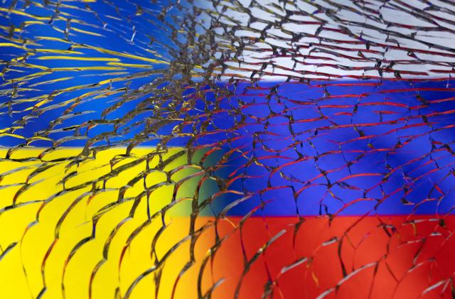 Ukraine and Russian flags are seen through broken glass in this illustration taken March 1, 2022. REUTERS/Dado Ruvic/Illustration