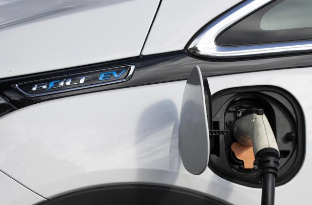 Tigard, OR, USA - Oct 6, 2021: Closeup of a Chevy Bolt EV electric car charging at a public charging station in a parking lot in Tigard, Oregon.