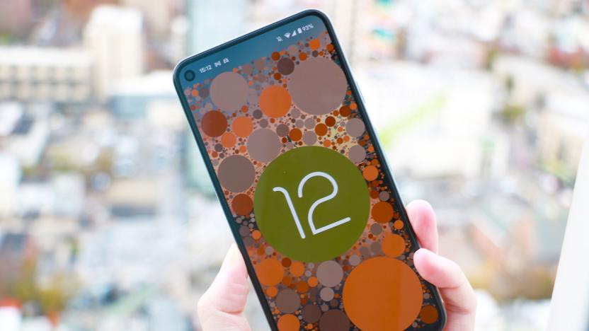 A phone showing the Android 12 easter egg, which is the OS logo on a background of circles themed to the system's color scheme.