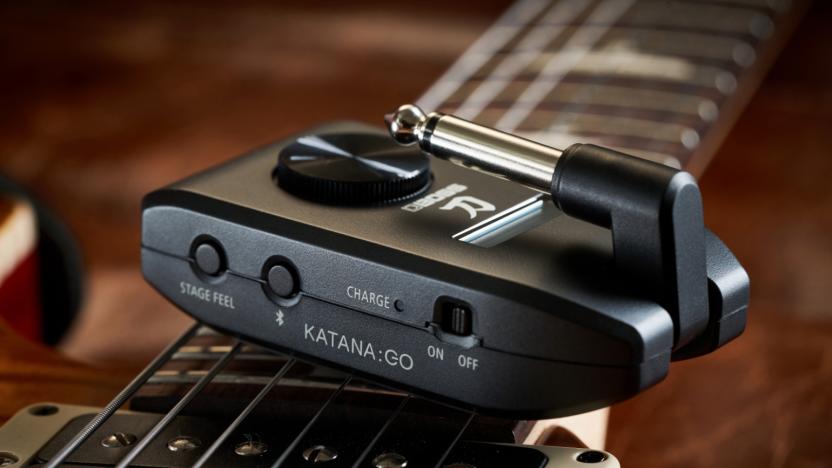 A headphone amp on top of a guitar.