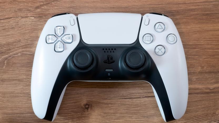Closeup photo of a PS5 DualSense controller (white) sitting on a brown wooden surface.