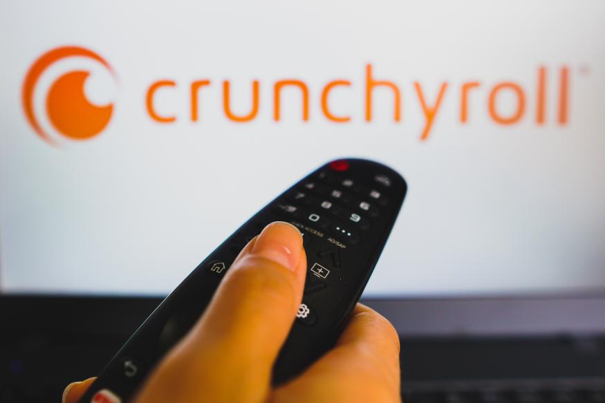 BRAZIL - 2022/05/10: In this photo illustration, a hand holding a TV remote control in front of the Crunchyroll logo on a TV screen. (Photo Illustration by Rafael Henrique/SOPA Images/LightRocket via Getty Images)