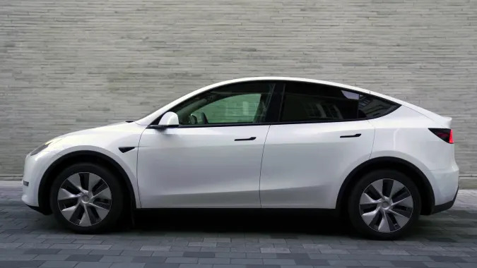 Kentucky, United States - February 27, 2022: Side view of a white Tesla Model Y, parked on the street, of a city. In the background a building.