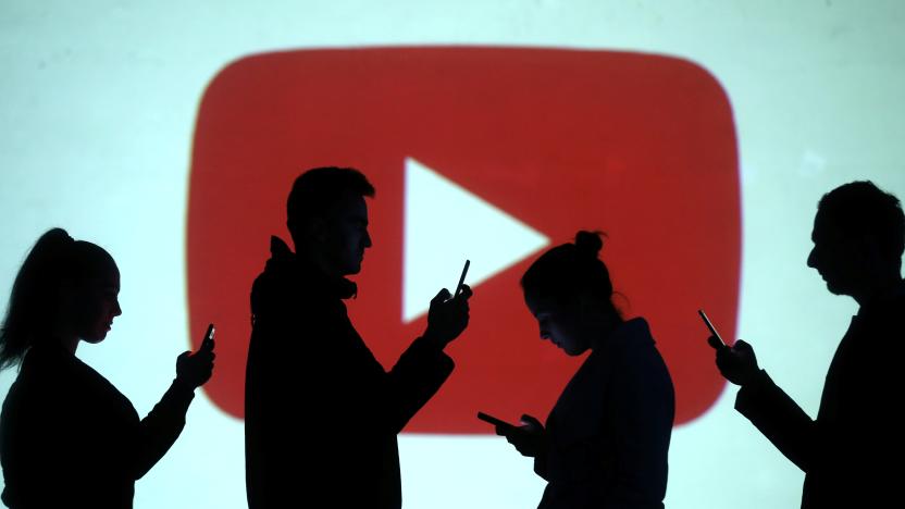 Silhouettes of mobile users are seen next to a screen projection of Youtube logo in this picture illustration taken March 28, 2018.  REUTERS/Dado Ruvic/Illustration