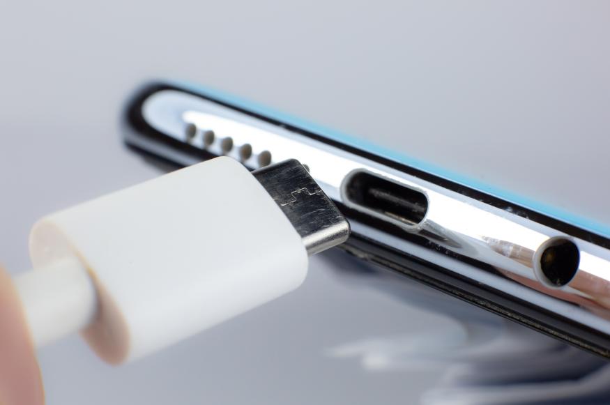 Man connecting USB Type C Port Cable for charging to the smartphone. Close up photo.