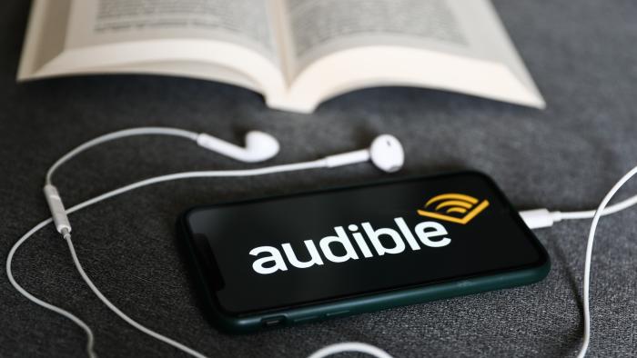 Audible logo displayed on a phone, headphones and a book are seen in this illustration photo taken in Krakow, Poland on August 22, 2022. (Photo by Jakub Porzycki/NurPhoto via Getty Images)