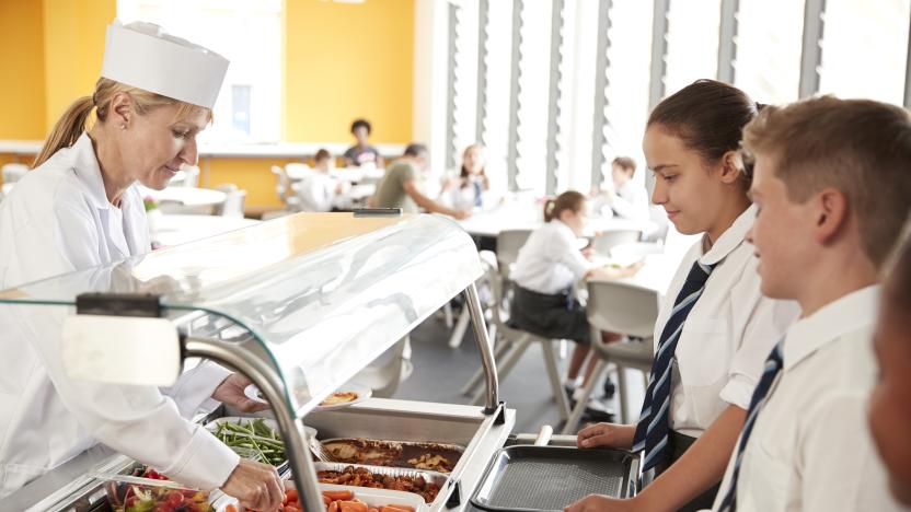 High School Students Wearing Uniform Being Served Food In Canteen