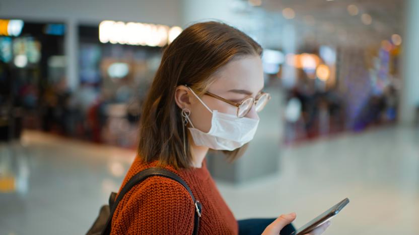 Teenager wearing medical mask protecting herself against virus in a food court of a shopping mall or airport lobby