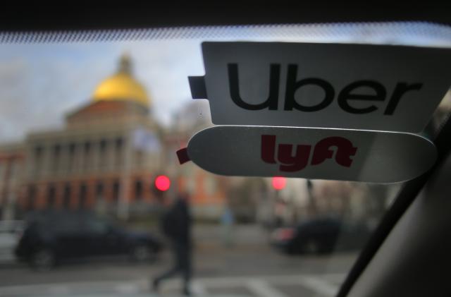 BOSTON, MA - NOVEMBER 14: Uber and Lyft stickers are pictured inside a ride share vehicle outside the Massachusetts State House in Boston on Nov. 14, 2019. Many drivers pick up fares for both companies. That boxy delivery truck blocking your lane is just one maddening manifestation of a public failure to adapt to the new convenience economy. The technology built around our desire for instant gratification - Uber and Lyft, DoorDash and Grubhub, the Amazon packages whizzing from distribution centers to our doorsteps - has become the source of huge amounts of new traffic. Hundreds of thousands of these trips would never have happened just a few years ago. But the public policy response has been no match for this challenge, the Globe Spotlight Team has found. In Boston, in fact, the operative policy only enables the offender. It is part of a pattern of delayed or passive public response to our slow-moving crisis in commuting. True, state officials were a nose ahead of the pack in imposing a surcharge on Uber and Lyft rides three years ago - an attempt at the time to make the companies pay their share of transportation costs - but now they have fallen out of the vanguard. Confronted by the powerful ride-share lobby on Beacon Hill, state leaders havent summoned the will or nerve to impose the kind of high fees and stringent limits other cities are using to try to curb the traffic. (Photo by Lane Turner/The Boston Globe via Getty Images)