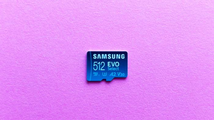 A light blue microSD card, the Samsung Evo Select, rest against a pink background.  