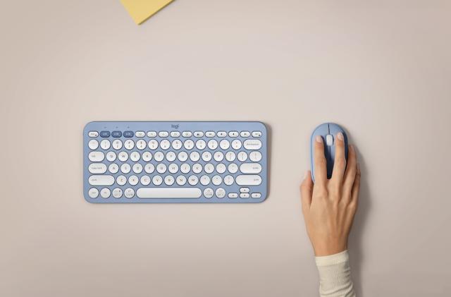 a blue keyboard sits next to a blue mouse being grabbed by a hand. 