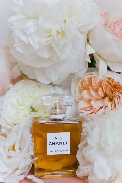 A bottle of chanel perfume next to a hat and flowers photo – Free