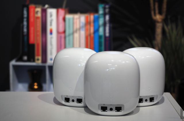 Image of three Nest WiFi Pro units, rear-on, in front of a blurred bookcase.