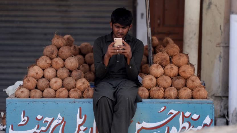 A Pakistani vendor uses his smartphone as he waits for customers at his stall at a market in Islamabad on October 11, 2018. (Photo by AAMIR QURESHI / AFP)        (Photo credit should read AAMIR QURESHI/AFP via Getty Images)