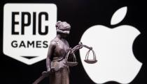 3D printed Lady Justice figure is seen in front of displayed Apple and Epic Games logos in this illustration photo taken February 17, 2021. REUTERS/Dado Ruvic/Illustration