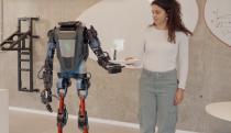 A lady handing a robot a plate.