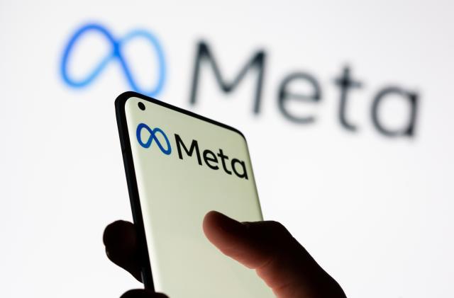 Woman holds smartphone with Meta logo in front of a displayed Facebook's new rebrand logo Meta in this illustration picture taken October 28, 2021. REUTERS/Dado Ruvic/Illustration