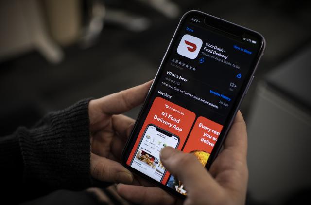 An AFP journalist checks the DoorDash food delivery application on her smartphone on February 27, 2020 in Washington, DC. - DoorDash on February 27, 2020 began the process of going public with a US stock offering that could value the popular restaurant meal delivery service at more than $10 billion.
San Francisco-based DoorDash said it confidentially registered with market regulators at the Securities and Exchange Commission for an initial public offering of shares.
The price and number of shares had yet to be determined. DoorDash backers including Japanese financial titan Softbank have pumped more than $2 billion into the startup, which last year was given a valuation of nearly $13 billion. (Photo by Eric BARADAT / AFP) (Photo by ERIC BARADAT/AFP via Getty Images)