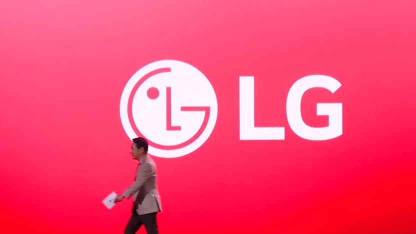 Screenshot of an LG executive walking to camera-left in front of an enormous screen showing an LG logo against a red background.