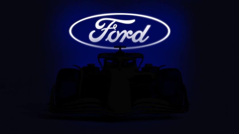 A brightly-lit Ford logo sits above a Formula 1 car shrouded in shadow.