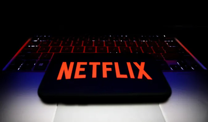 Netflix logo displayed on a phone screen and a laptop keyboard are seen in this illustration photo taken in Krakow, Poland on January 7, 2022. (Photo by Jakub Porzycki/NurPhoto via Getty Images)