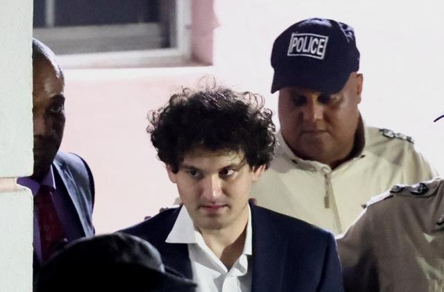 Sam Bankman-Fried, who founded and led FTX until a liquidity crunch forced the cryptocurrency exchange to declare bankruptcy, is escorted out of the Magistrate Court building after his arrest in Nassau, Bahamas December 13, 2022.  REUTERS/Dante Carrer