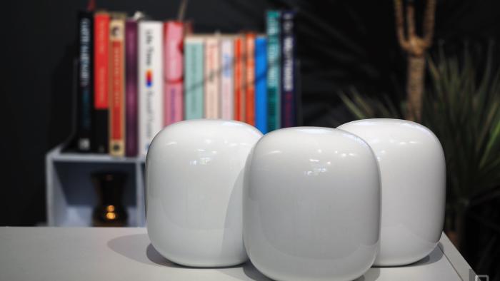 Image of three Nest WiFi Pro units on a table in front of a blurred bookshelf.