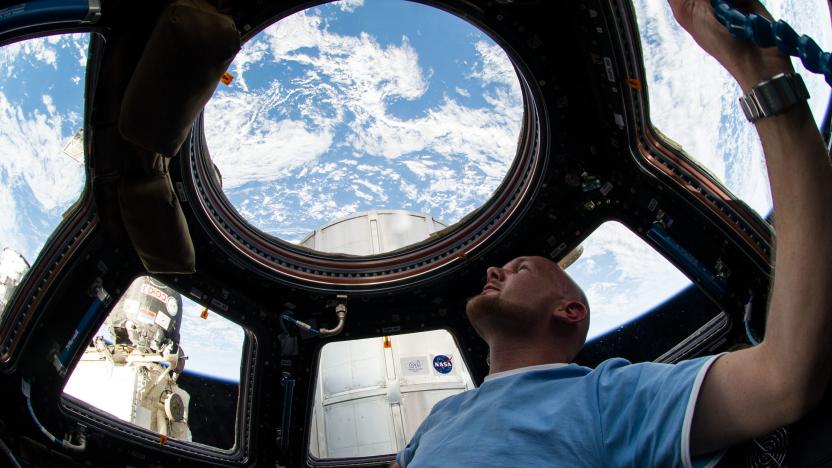 European Space Agency astronaut Alexander Gerst, Expedition 40 flight engineer, enjoys the view of Earth from the windows in the Cupola of the International Space Station. A blue and white part of Earth is visible through the windows.