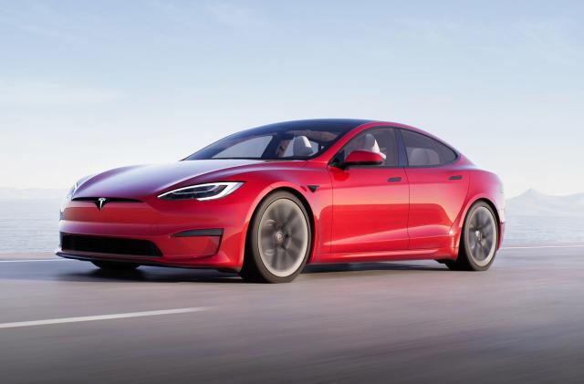 A Tesla Model S Plaid in red races down a coastal highway.